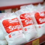 Sacos de açúcar embalados organizados em uma prateleira de supermercado.