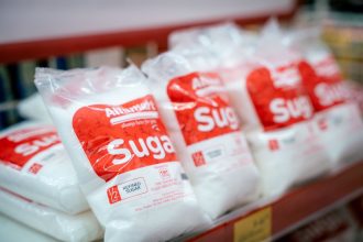 Sacos de açúcar embalados organizados em uma prateleira de supermercado.