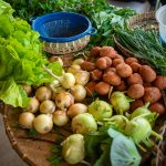 Batatas, cebolas e alface frescas expostas em uma banca de mercado.