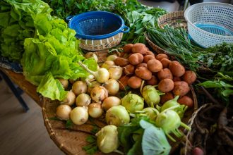 Batatas, cebolas e alface frescas expostas em uma banca de mercado.