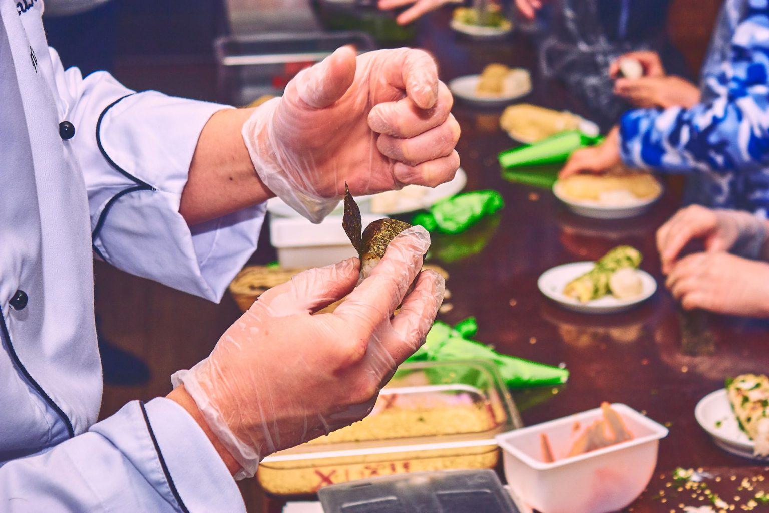Chef demonstra o preparo de um aperitivo durante uma aula de culinária.