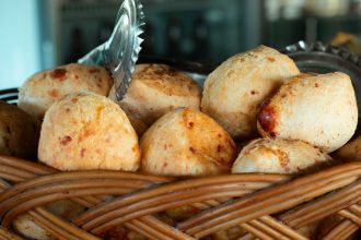Pães de queijo recém-assados em uma cesta trançada.