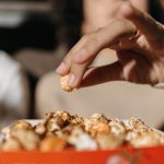 Mão alcança pipoca em uma sala de cinema, ilustrando a relação entre filmes e gastronomia.